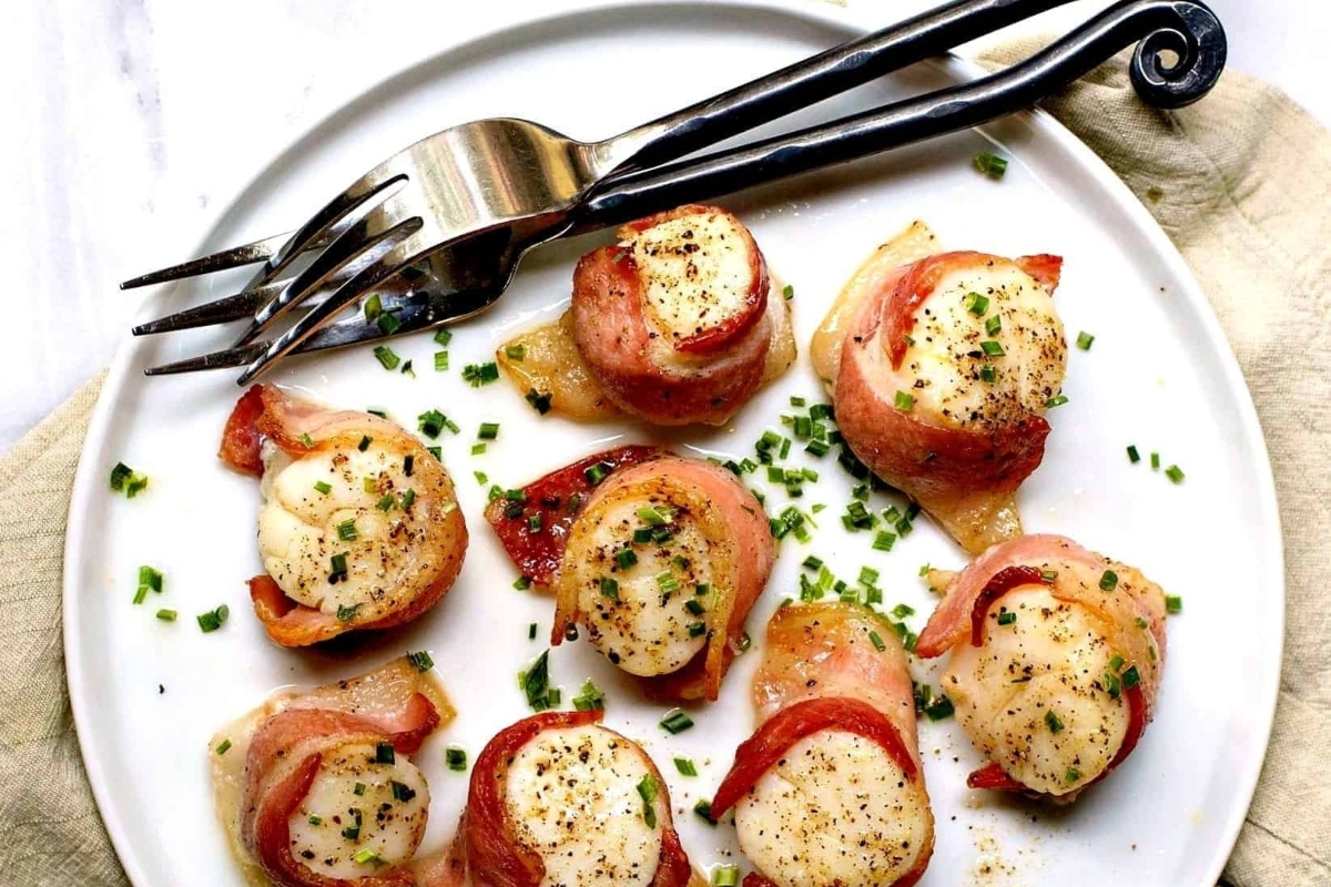 Bacon-wrapped ham and cheese bites served on a plate.