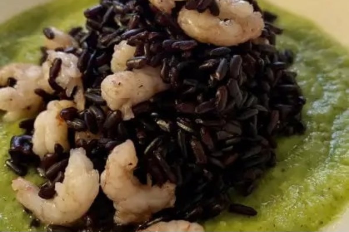 Feast of seven fishes featuring black rice with shrimp and green sauce.