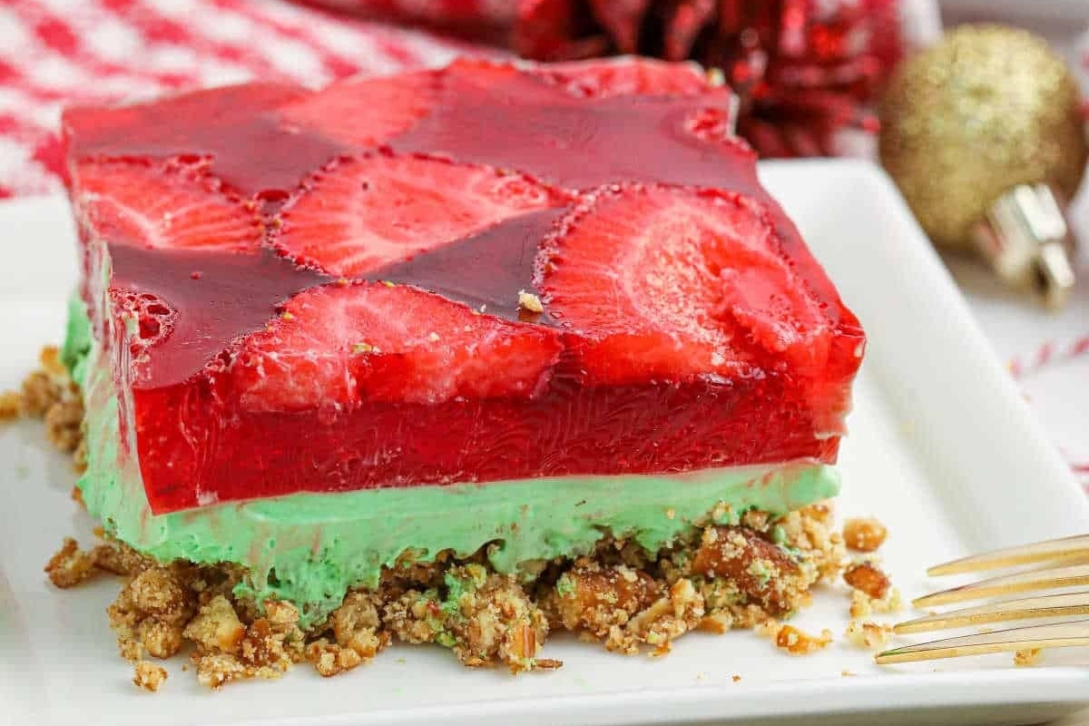 A slice of strawberry and green jello cake on a plate.
