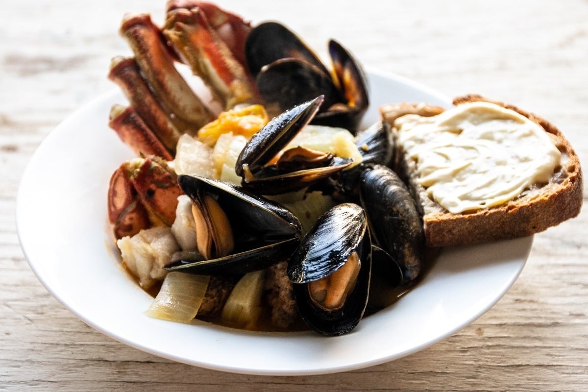 A feast of mussels and bread on a wooden table, reminiscent of the feast of seven fishes.