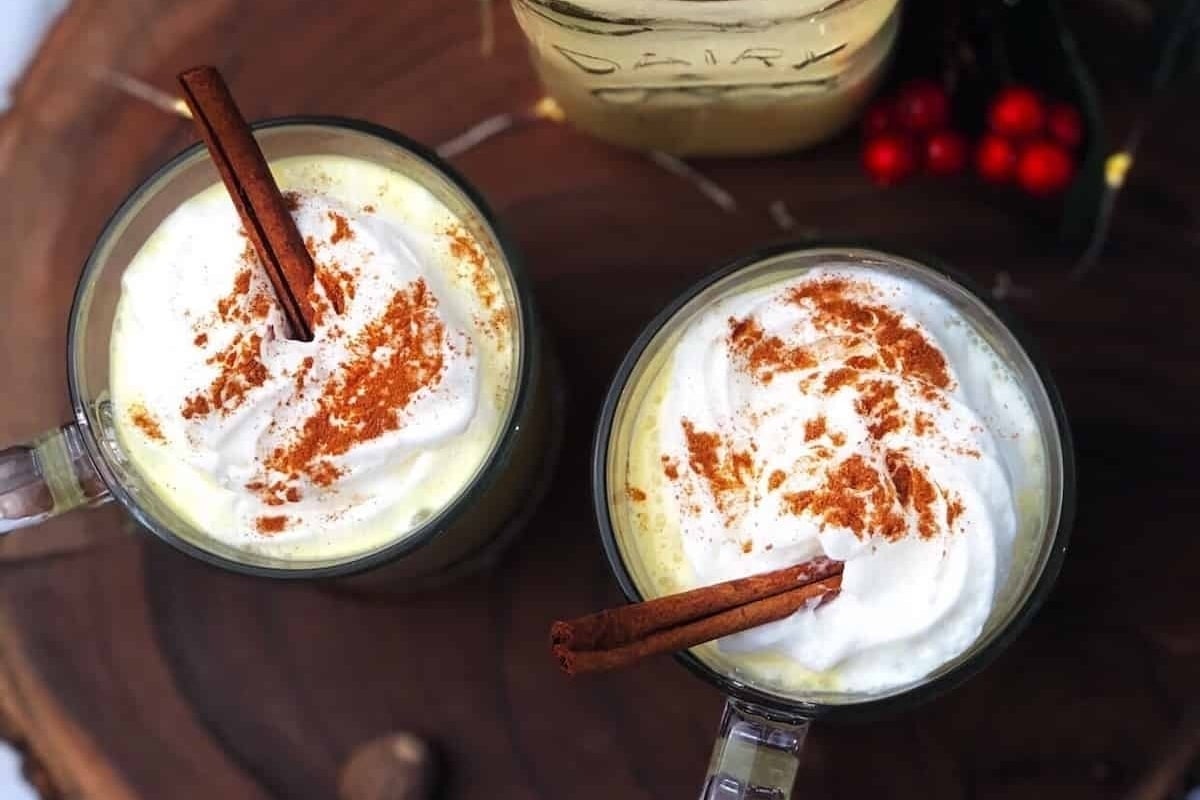 Two mugs of hot cocoa with cinnamon whipped cream.