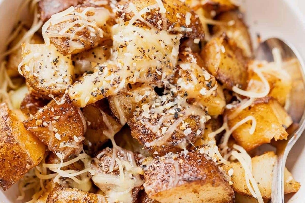 A slow cooker Christmas recipe for a bowl of cheesy potatoes served with a spoon.