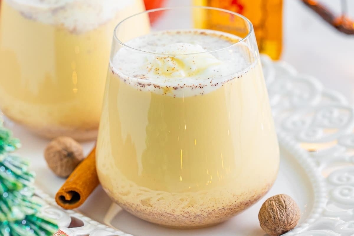 Two glasses of eggnog with cinnamon and whipped cream, the perfect recipe for indulging in festive eggnog drinks.