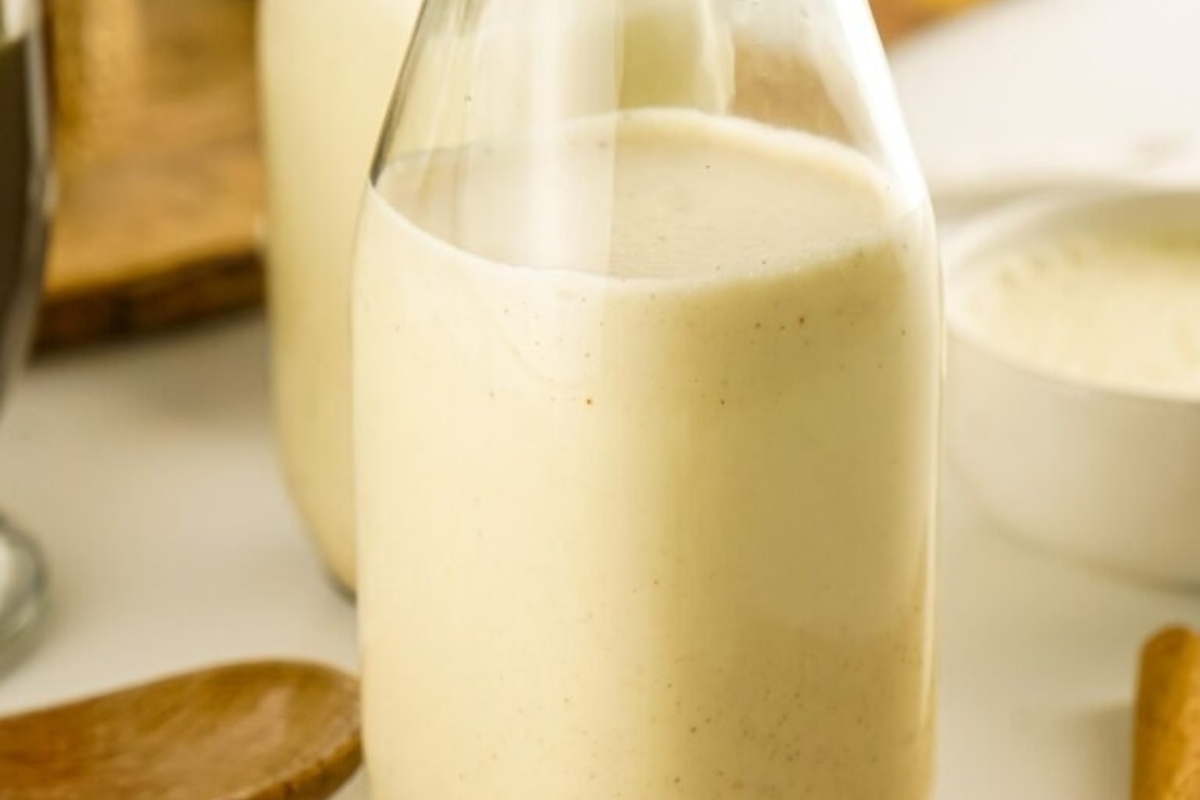 A bottle of eggnog and a spoon next to it.