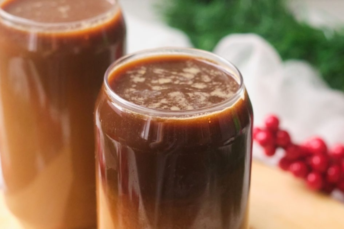 Two glasses of hot cocoa on a wooden cutting board, perfect for cozy winter drinks.