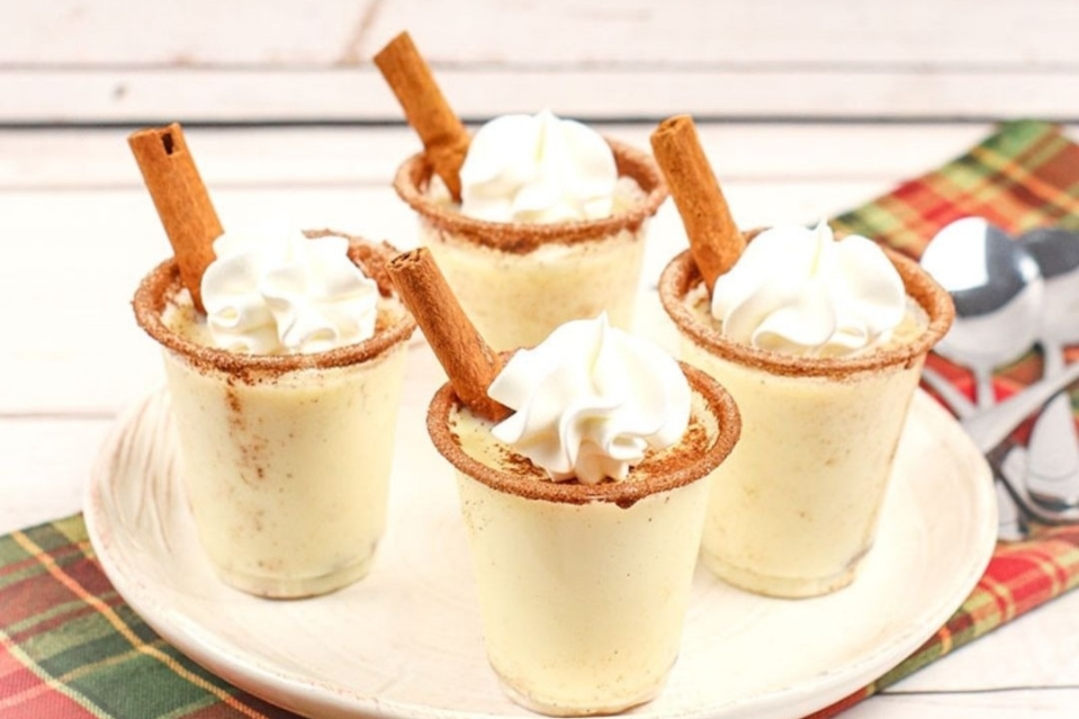 Whipped cream and cinnamon cups topped with eggnog on a plate.