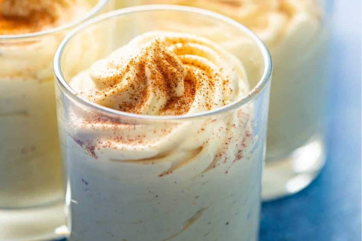 A creamy glass of eggnog with a dollop of cinnamon whipped cream.