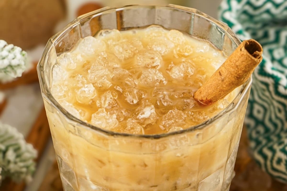 An eggnog drink with cinnamon and ice in a glass.
