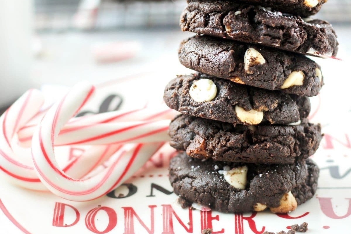 A stack of peppermint cookies on a plate with candy canes.