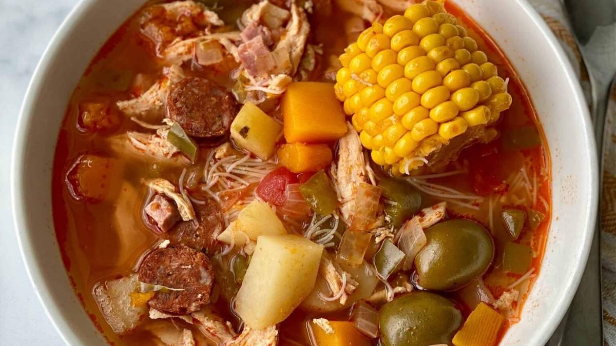 A bowl of soup with meat, vegetables and corn.