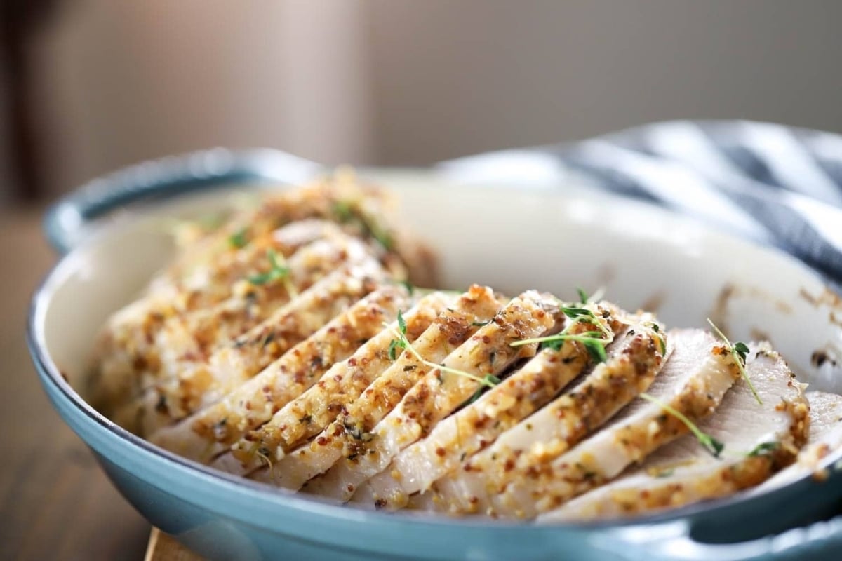 Sliced chicken in a blue dish on top of a wooden table, a perfect addition to New Year's dinners.