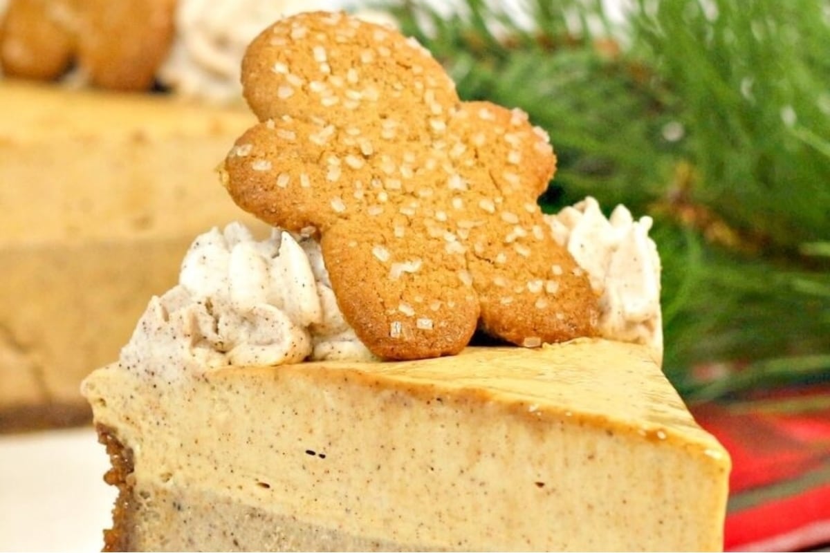 A holiday-inspired slice of pumpkin cheesecake topped with a gingerbread cookie.