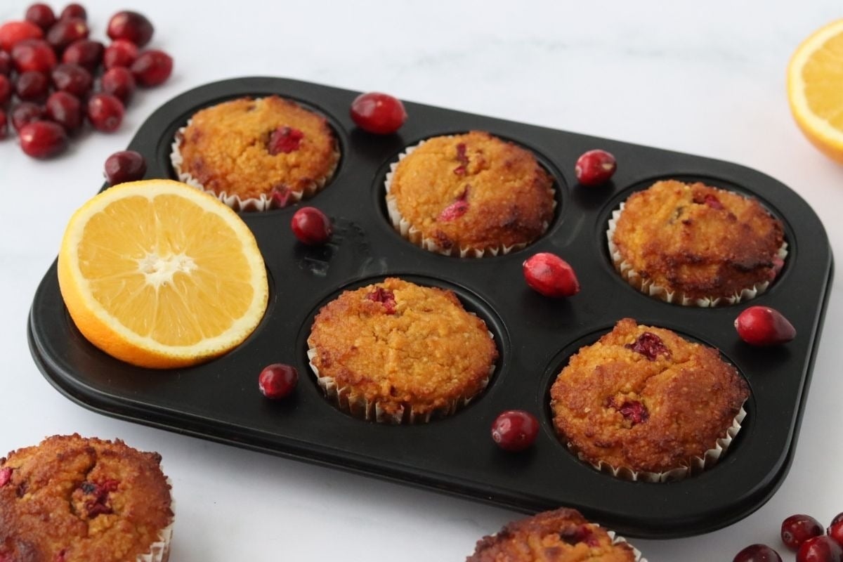 Delicious cranberry muffins in a muffin pan, topped with zesty orange slices.