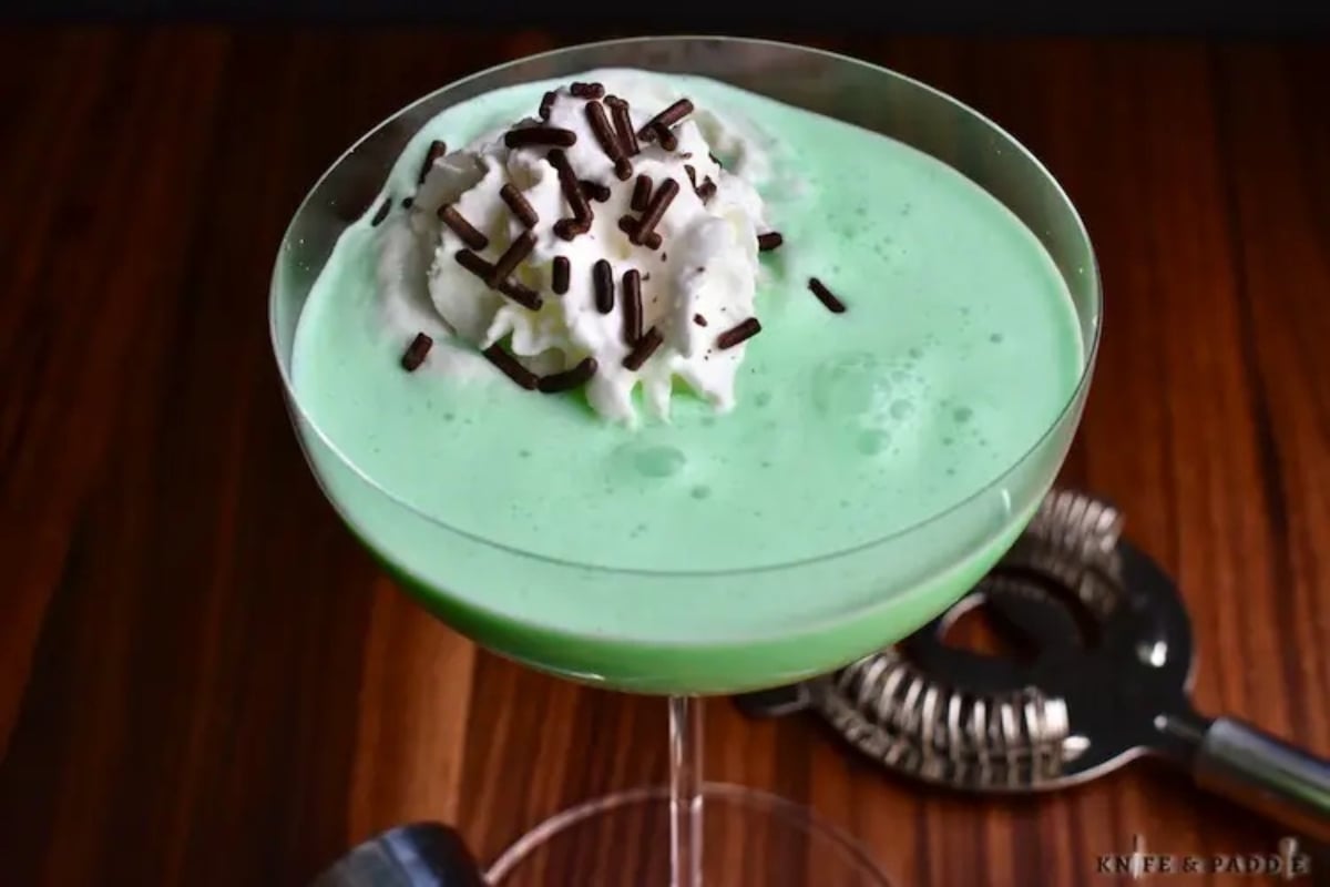 A festive green drink perfect for Christmas, topped with indulgent whipped cream and sprinkled with delightful chocolate chips.