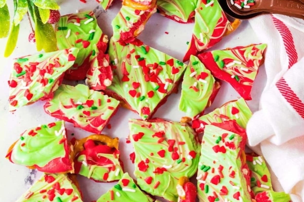 Christmas bark with red and green sprinkles on a white plate. This delectable treat is perfect for the holiday season and can be easily made using various Christmas bark recipes.