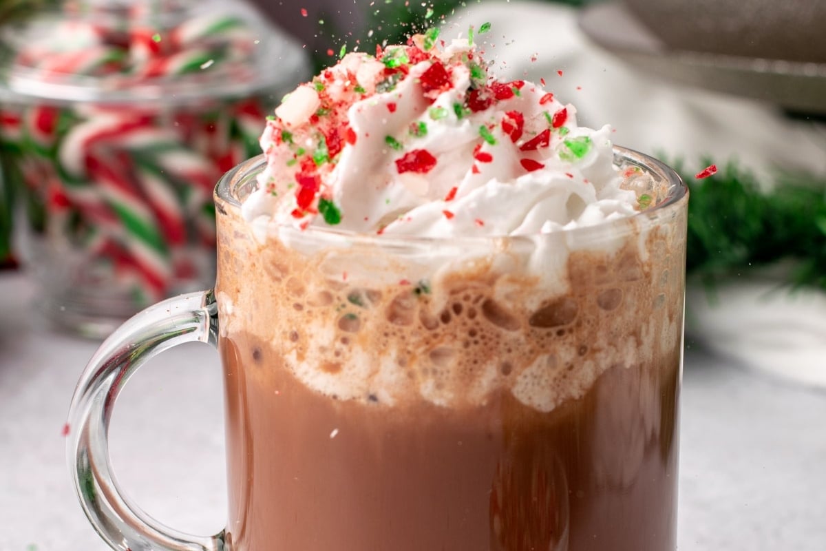 A Starbucks holiday cup of hot chocolate with whipped cream and candy canes.