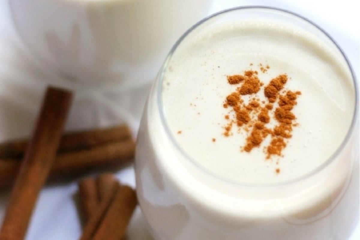 A glass of milk with cinnamon sticks.