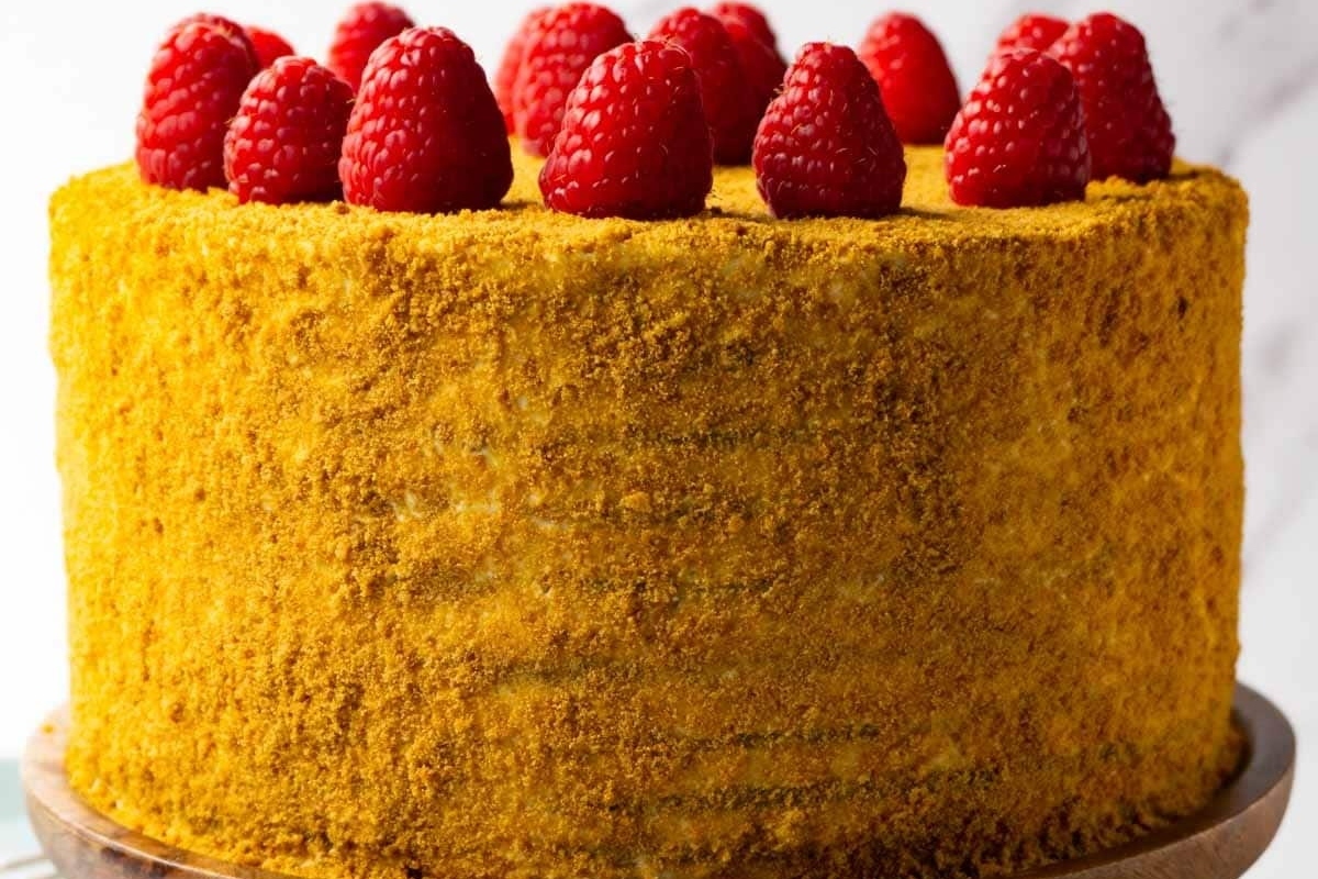 A festive Christmas cake adorned with juicy raspberries on top.