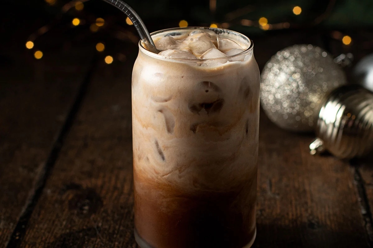 A Starbucks holiday iced coffee served in a glass on a wooden table.