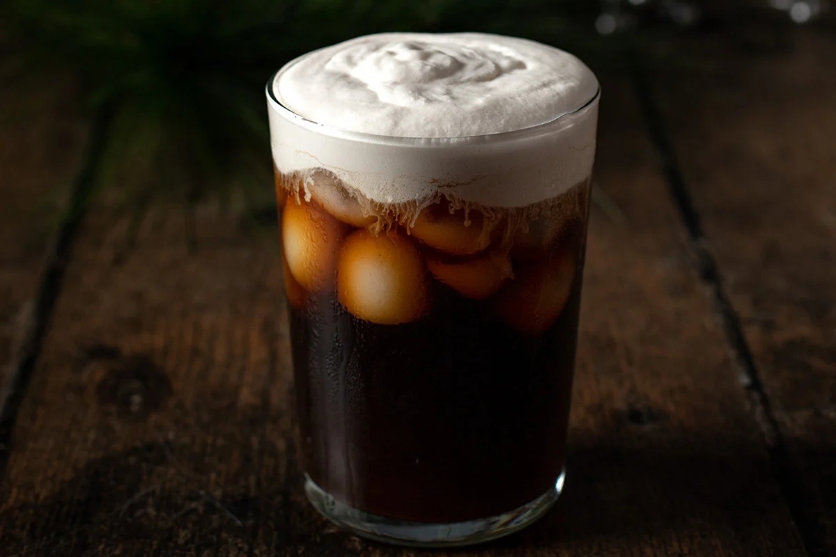 A festive glass of iced coffee with whipped cream on top, perfect for the Starbucks holiday season.