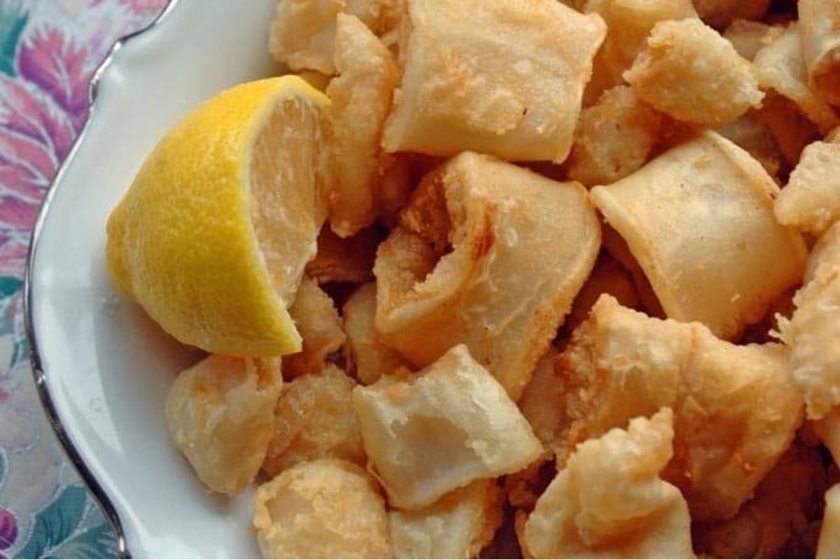 Fried octopus on a white plate with a lemon wedge, perfect for a feast of seven fishes!
