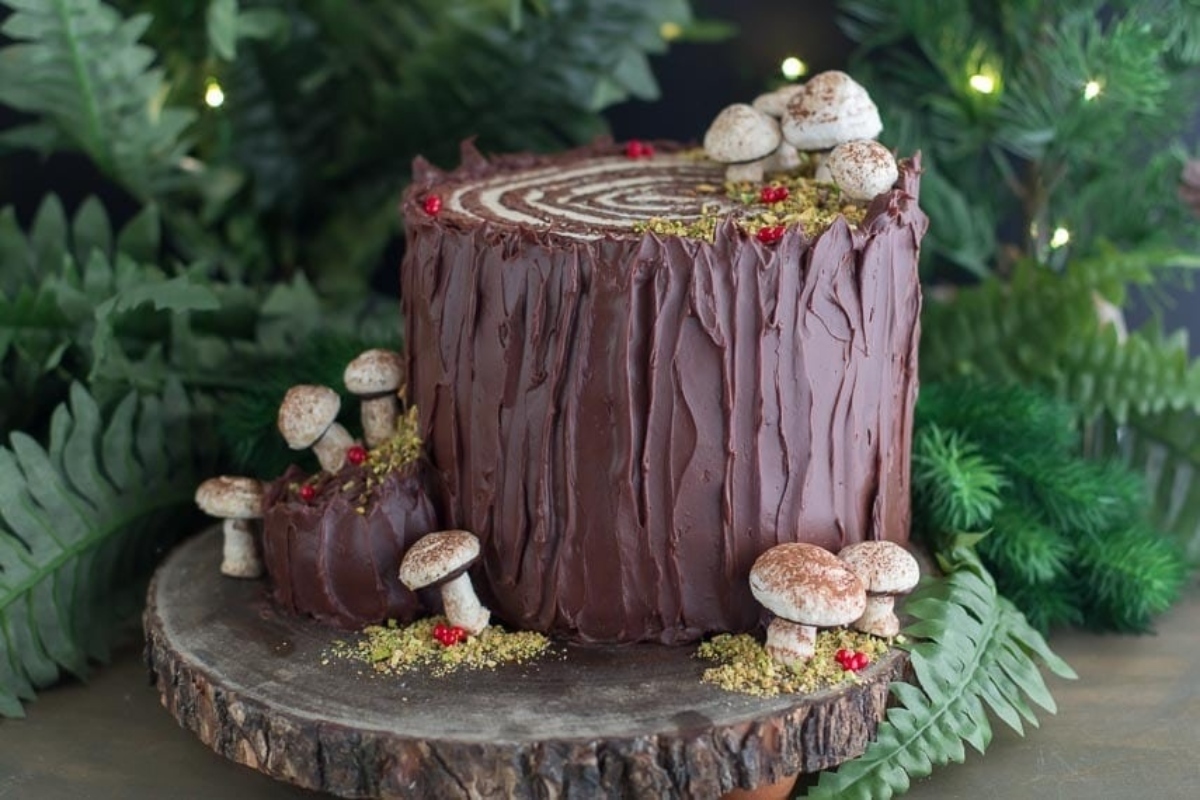 A festive chocolate cake adorned with mushrooms and greenery, perfect for Christmas celebrations.