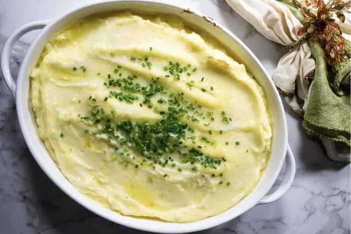 Make ahead mashed potatoes in a white dish with chives.
