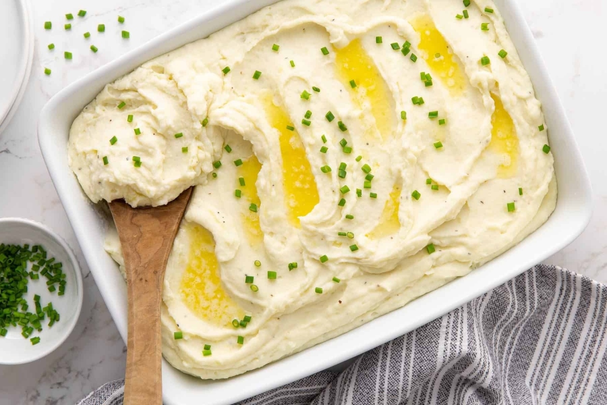 Make ahead holiday mashed potatoes in a white dish with chives.