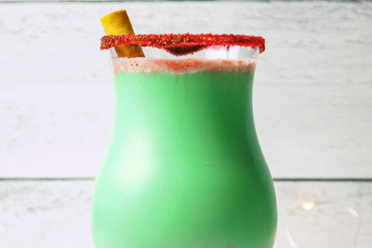 A festive green drink with a cinnamon stick on top.