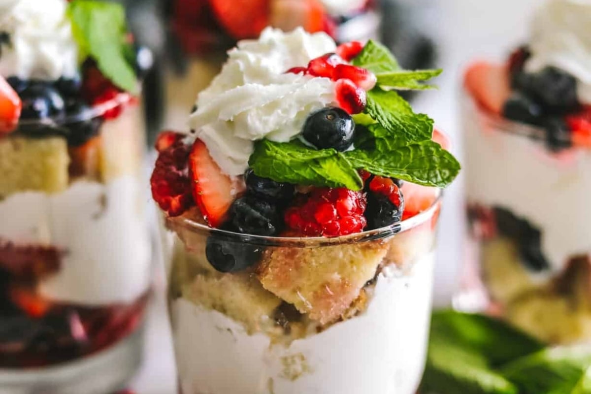 A Christmas trifle in a glass with whipped cream and berries.