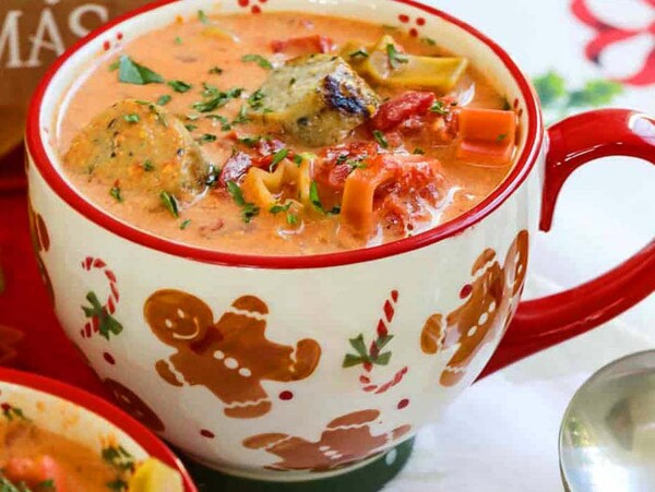 Festive mug of creamy soup with meatballs, pasta, and herbs, decorated with gingerbread figures—a cozy pick for slow cooker Christmas recipes.