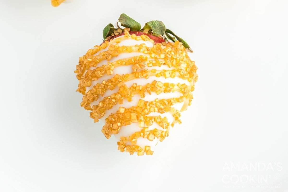 A white plate with two strawberries covered in icing, perfect for a New Year's eve party.