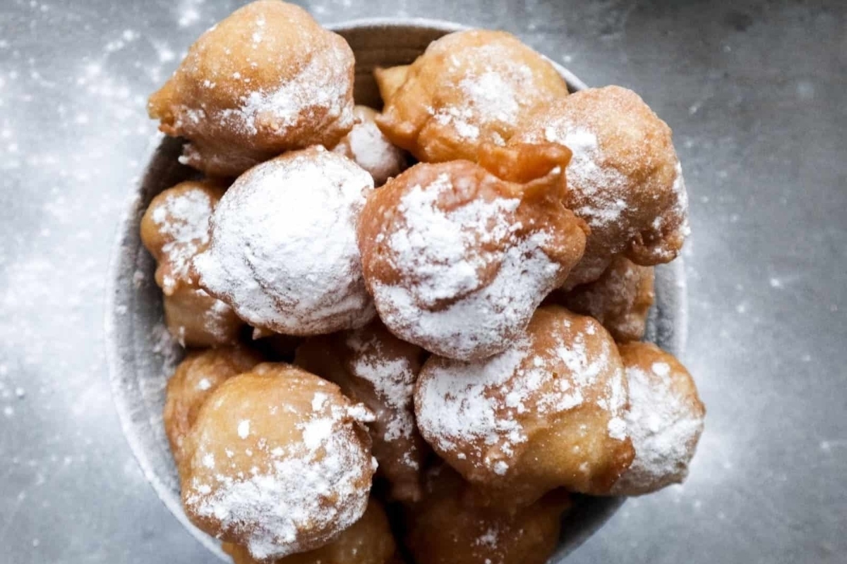 A bowl of powdered doughnuts and powdered sugar at a New Year's Eve party.