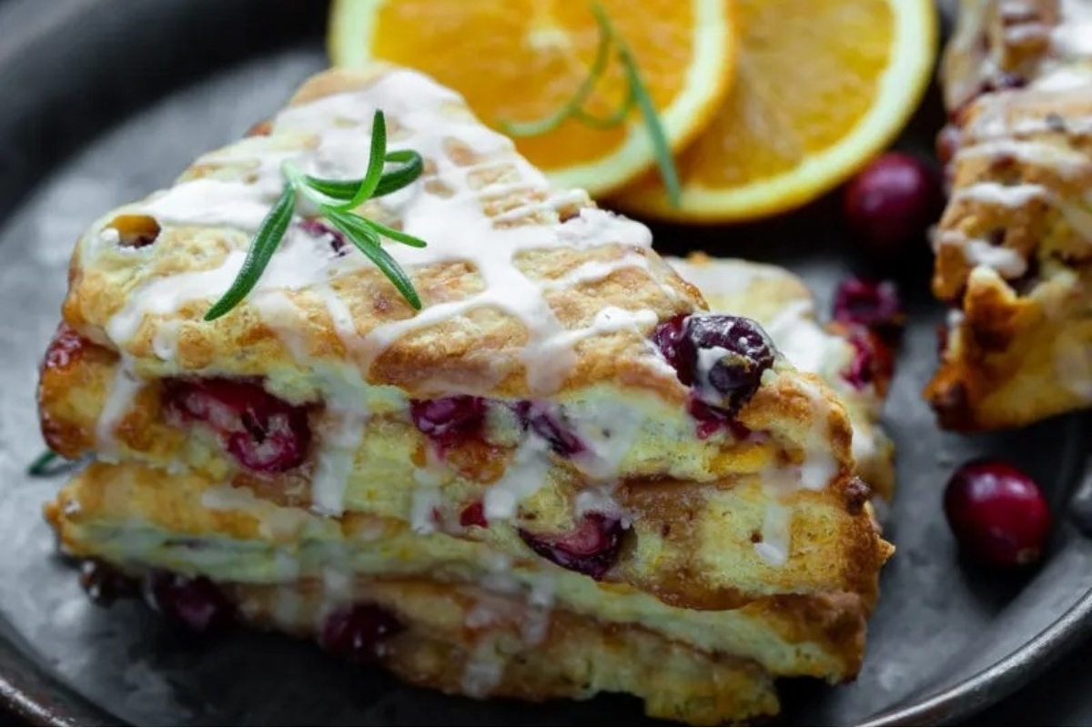 A stack of cranberry scones with orange slices and icing, perfect for a cranberry snack.