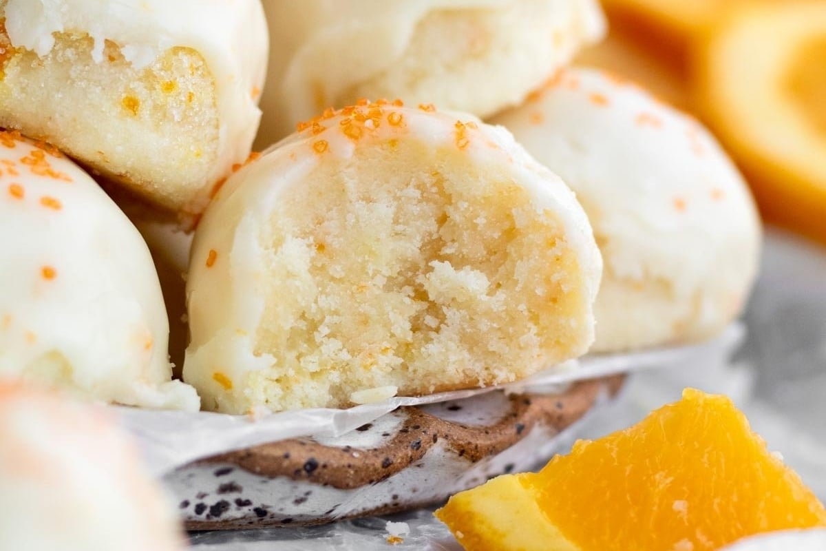 A plate of orange cookies with a bite taken out of them, perfect for freezable cookie recipes.