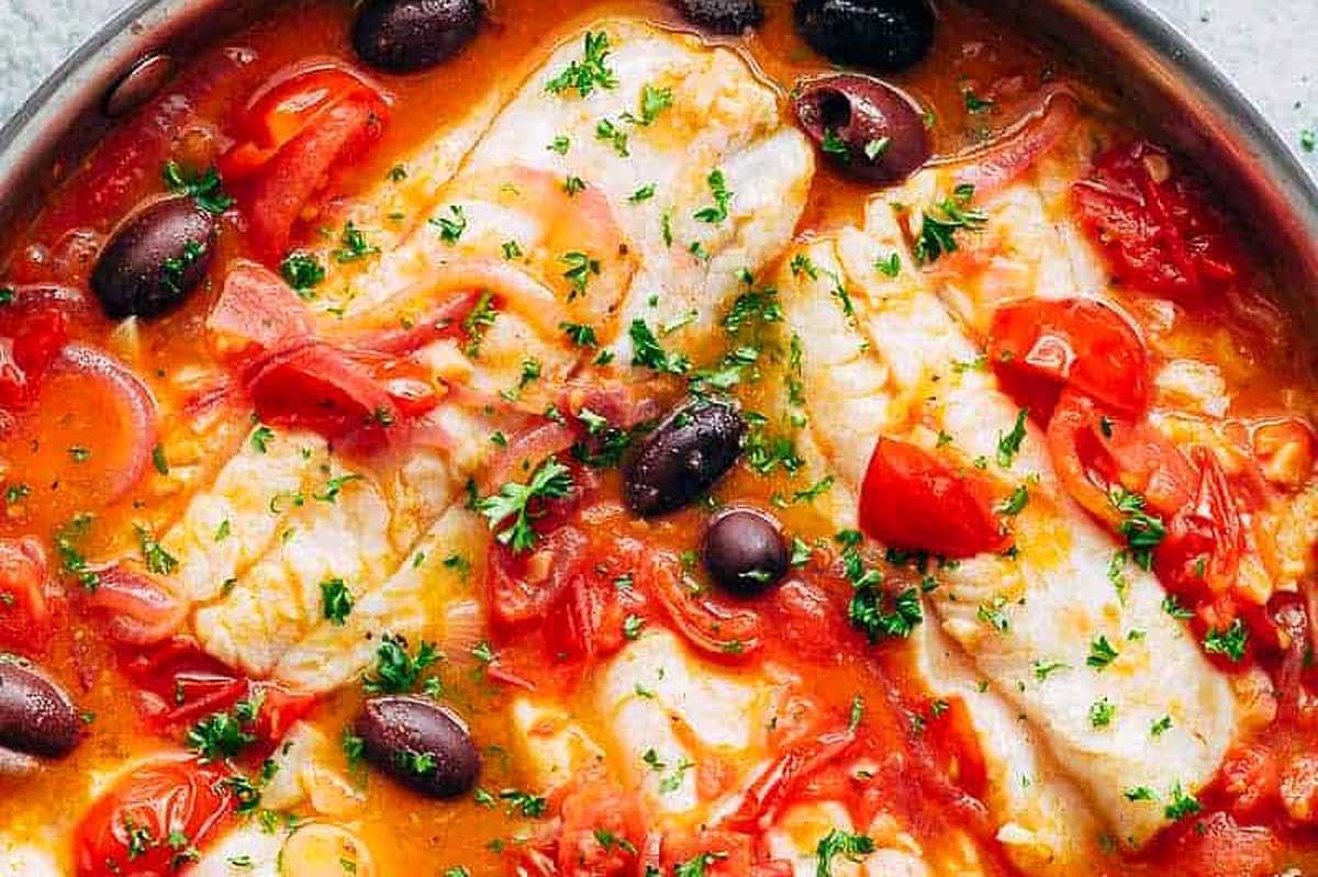 Feast of seven fishes featuring fish in tomato sauce cooked in a skillet.