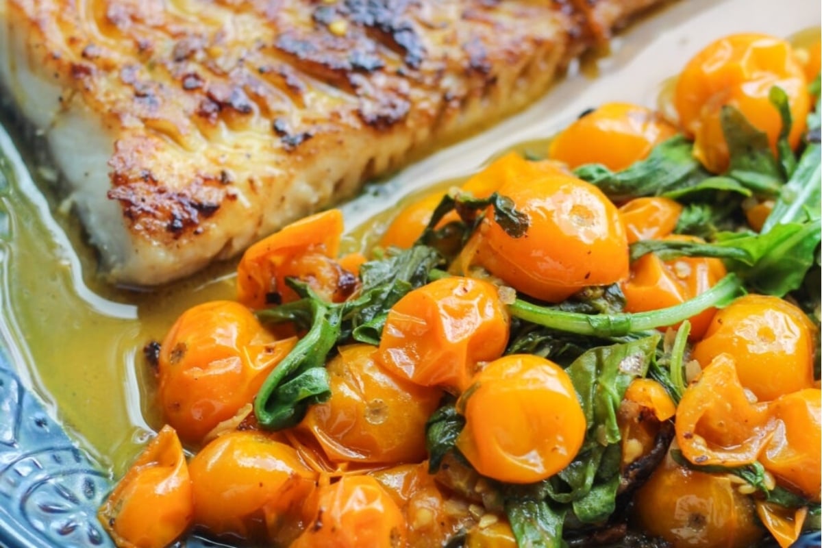 A plate of fish and tomatoes on a blue plate, perfect for the feast of seven fishes.