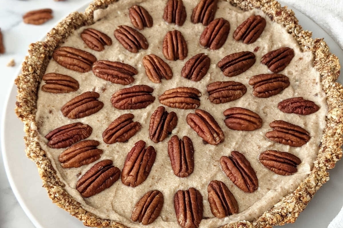 Make ahead holiday pecan pie on a white plate with pecans on top.
