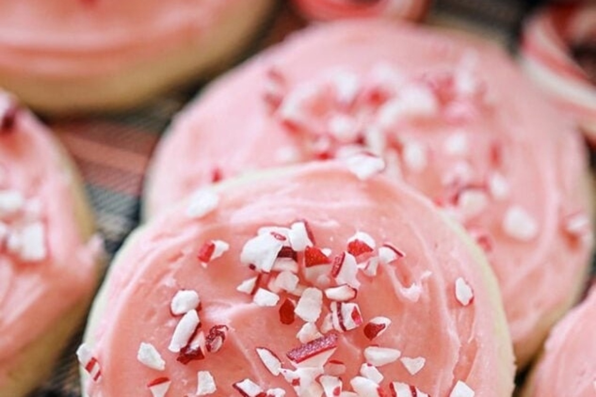 Peppermint frosted sugar cookies with candy canes on a cooling rack.