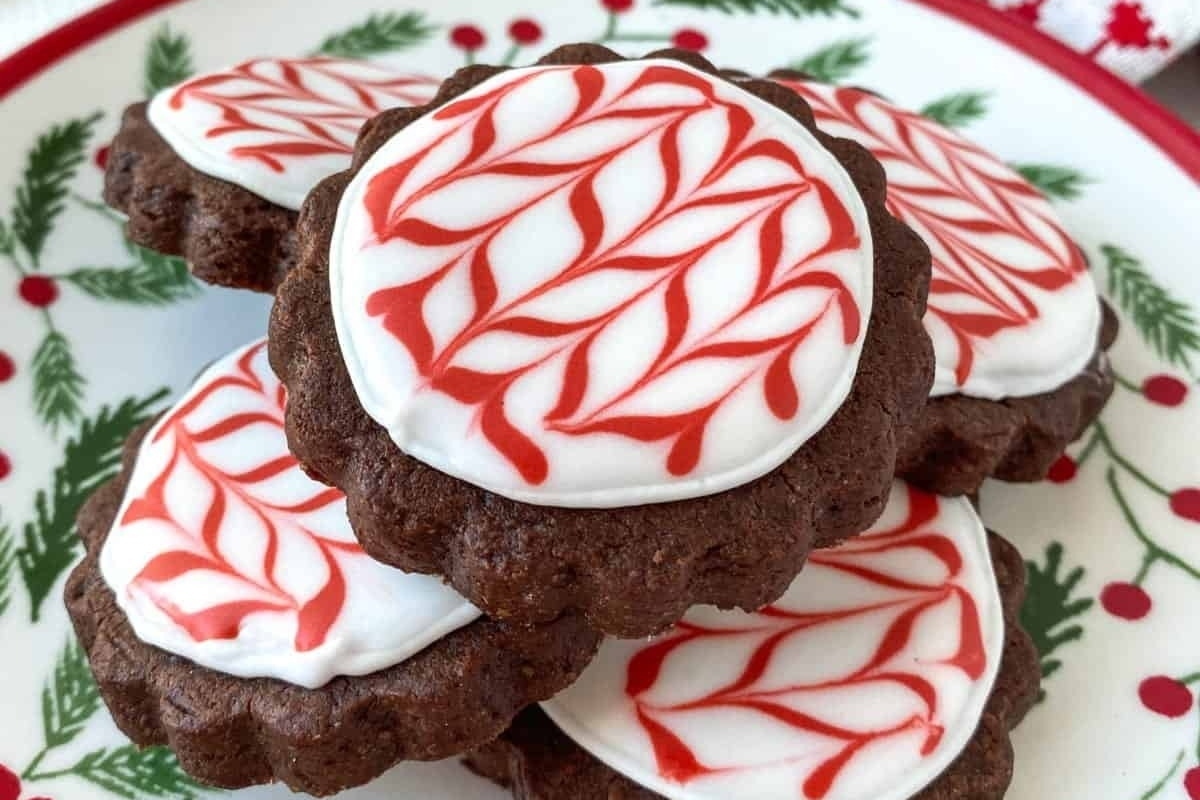Peppermint cookies with red and white icing sitting on a plate.