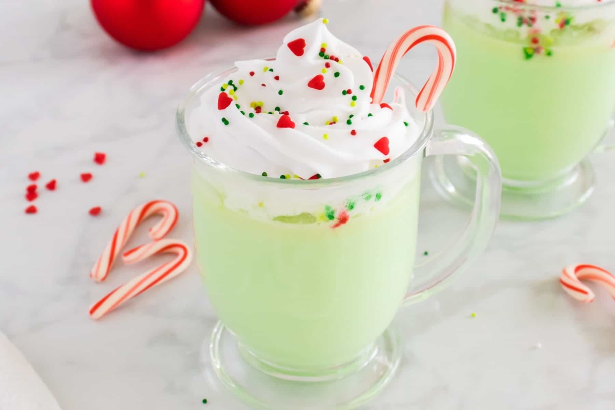 Enjoy a festive green drink adorned with decadent whipped cream and whimsical candy canes, perfect for the Christmas season.