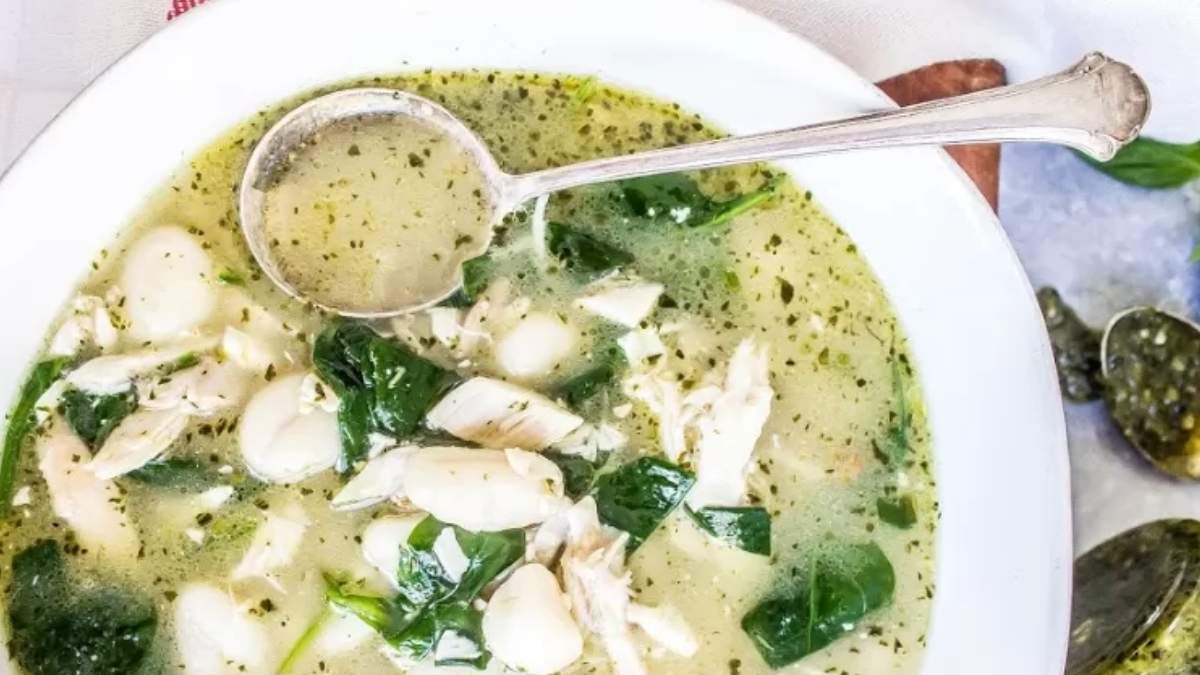 A bowl of chicken and spinach soup with a spoon.