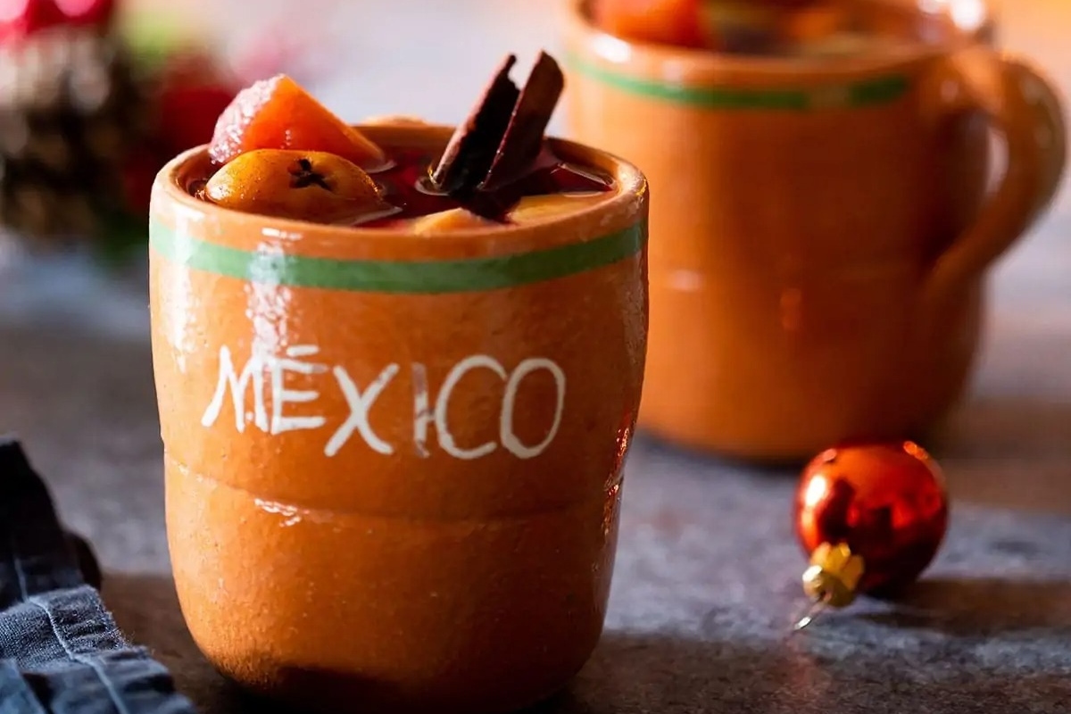 Two mugs of Mexican hot chocolate with cinnamon sticks, perfect for cozy Christmas festivities.