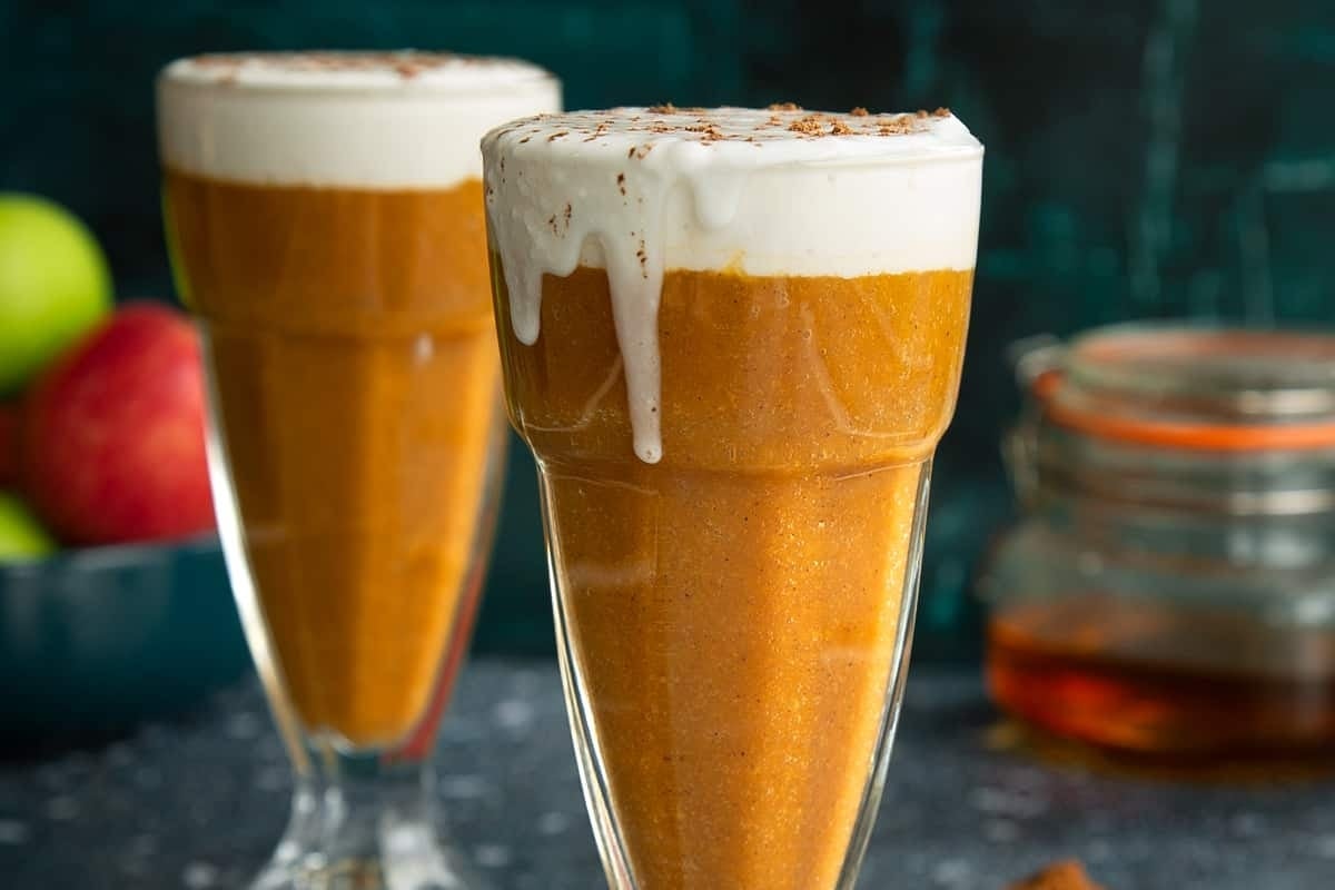 Two glasses of pumpkin spice latte with whipped cream and cinnamon at Starbucks during the holiday season.