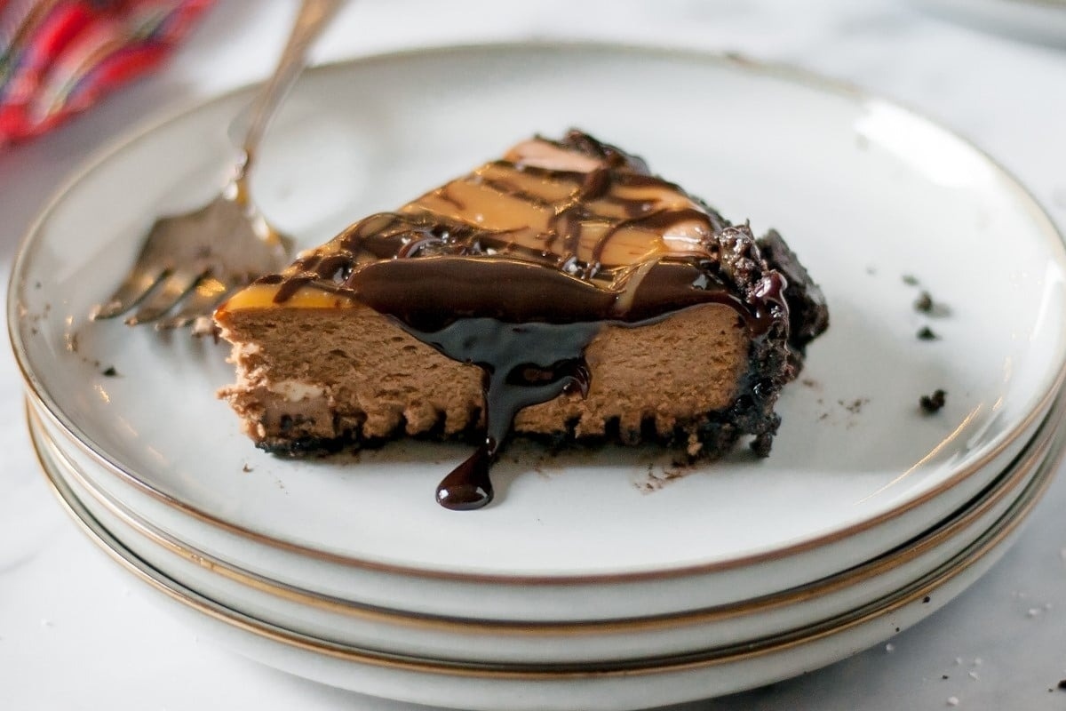 A holiday slice of chocolate cheesecake on a plate with a fork.