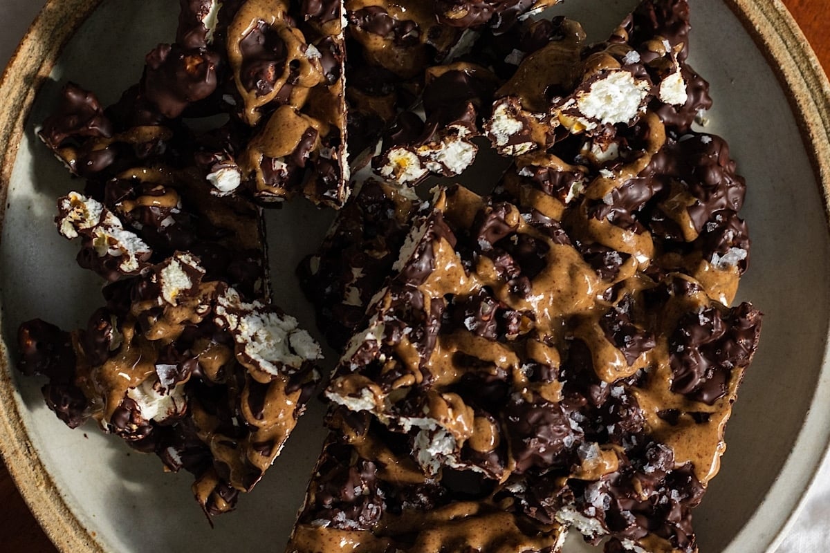A plate of Christmas bark, made with a combination of chocolate and peanut butter, placed on a rustic wooden table.