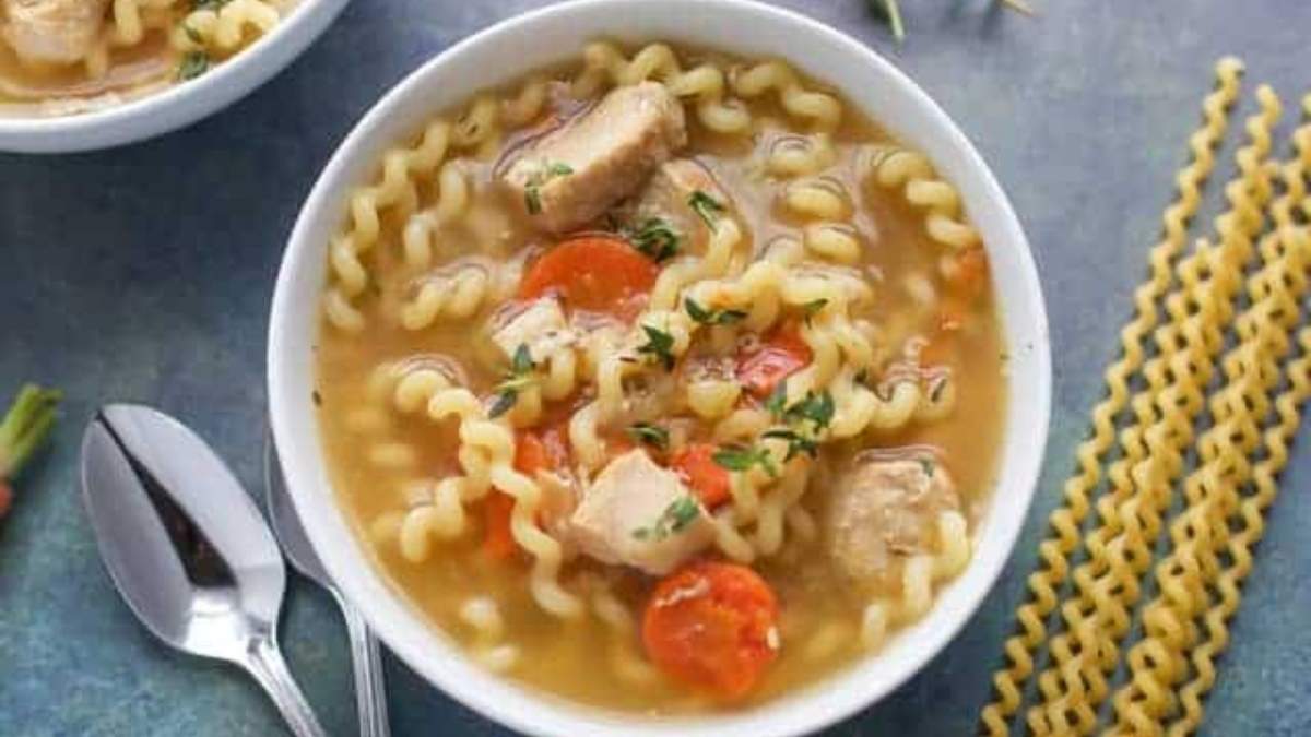 A bowl of chicken noodle soup with noodles and carrots.