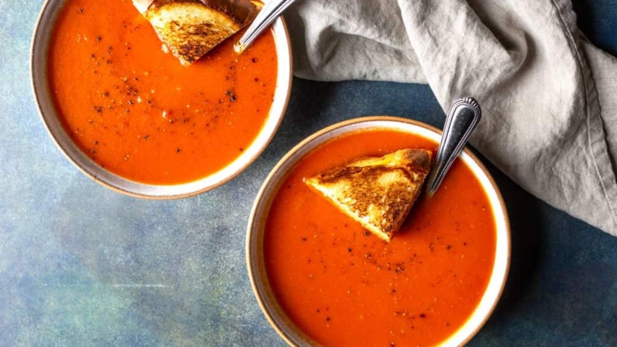 Two bowls of tomato soup with toasted bread.