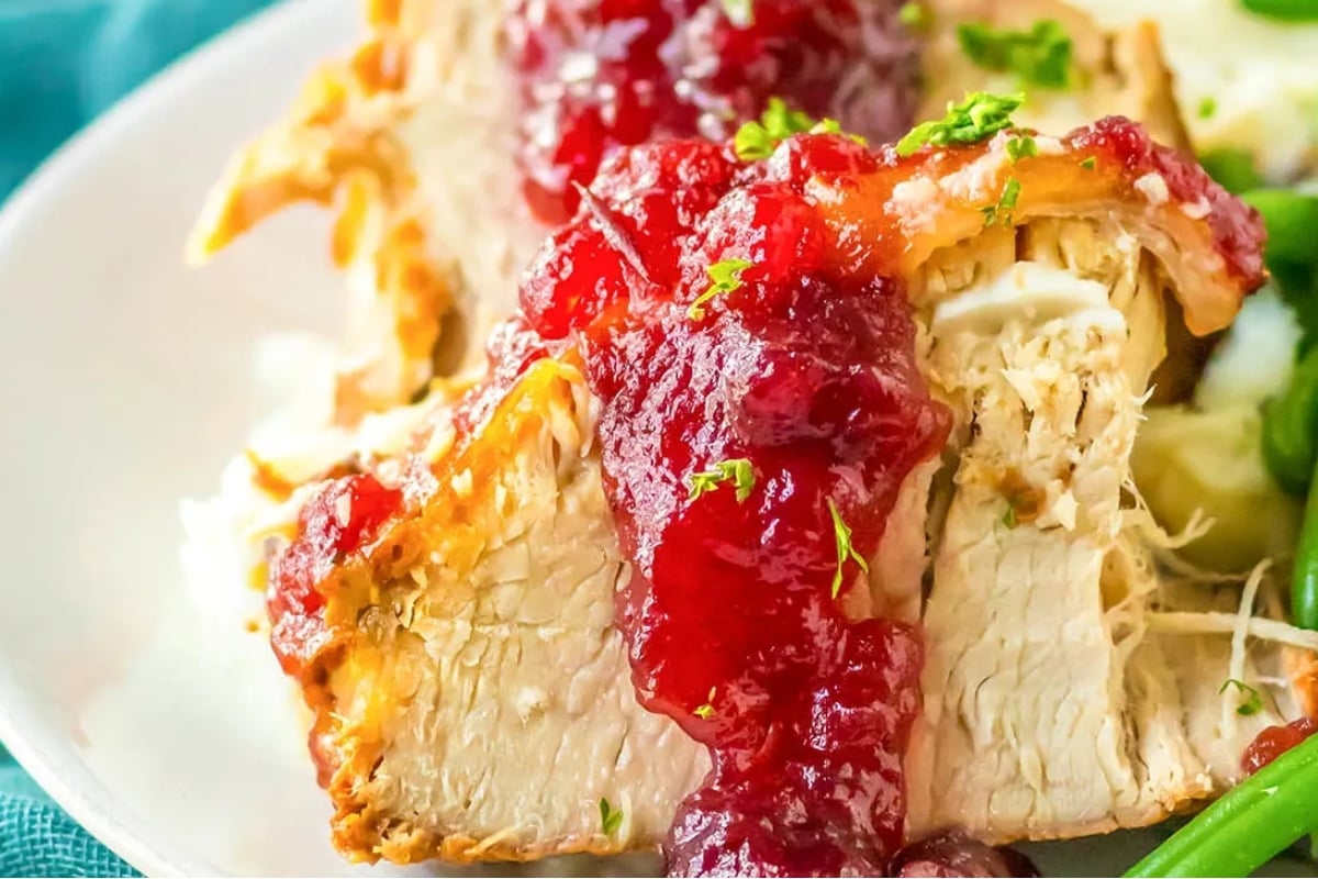 Slow cooker turkey with cranberry sauce and green beans on a plate.