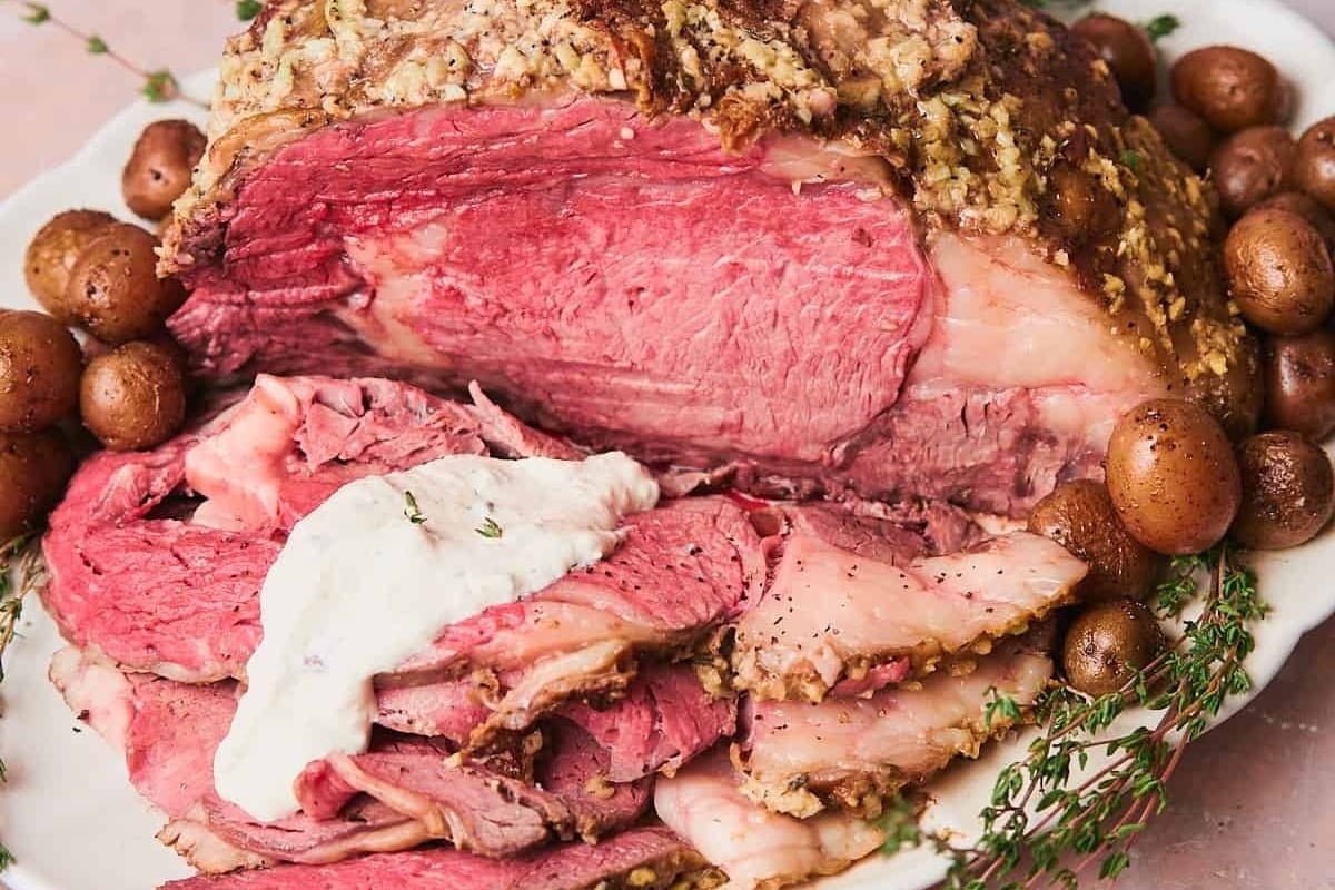 A delicious New Year's dinner featuring corned beef served on a plate alongside potatoes and sour cream.